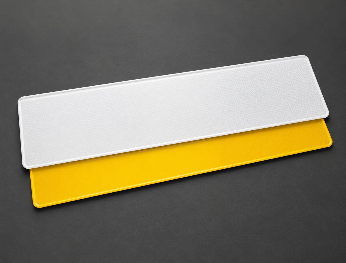 White reflective number plate blank stacked over a yellow reflective blank